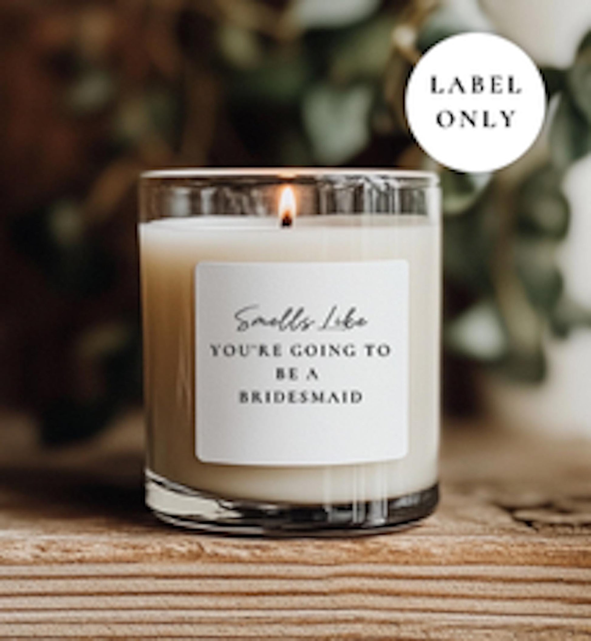 Candle with a label reading 'Smells Like You're Going to Be a Bridesmaid' on a wooden surface.