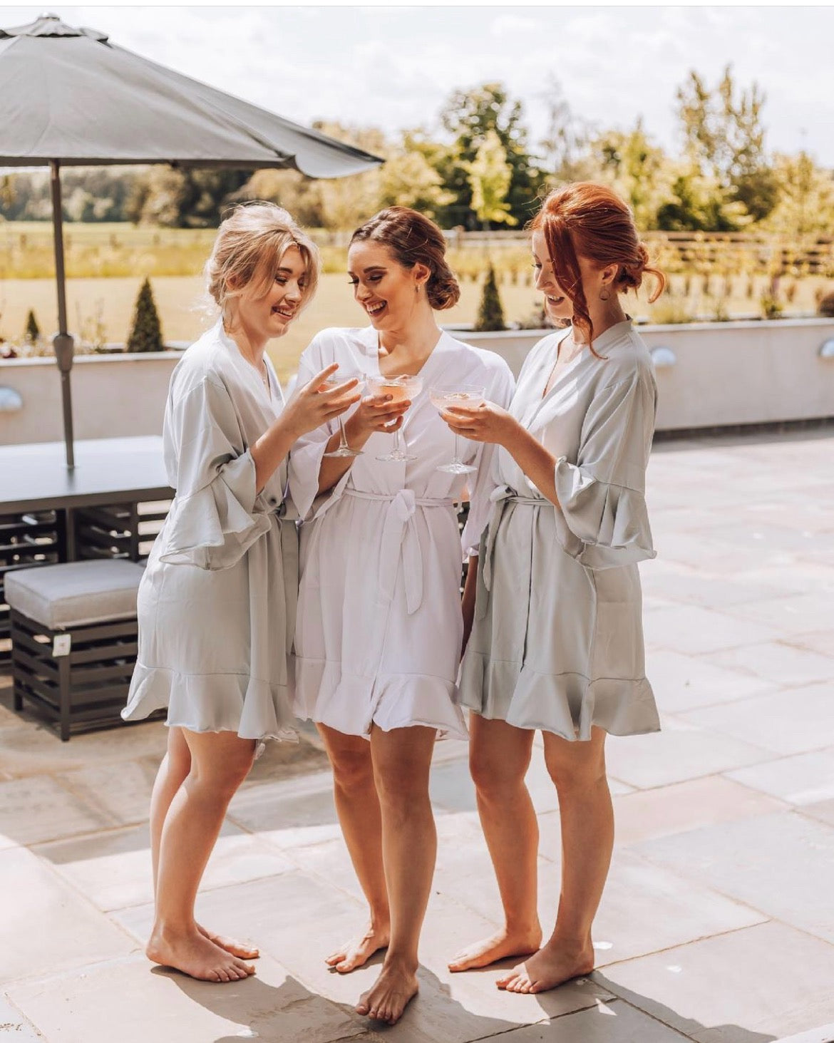 Bridesmaid in ruffle dressing gowns drinking outside hotel