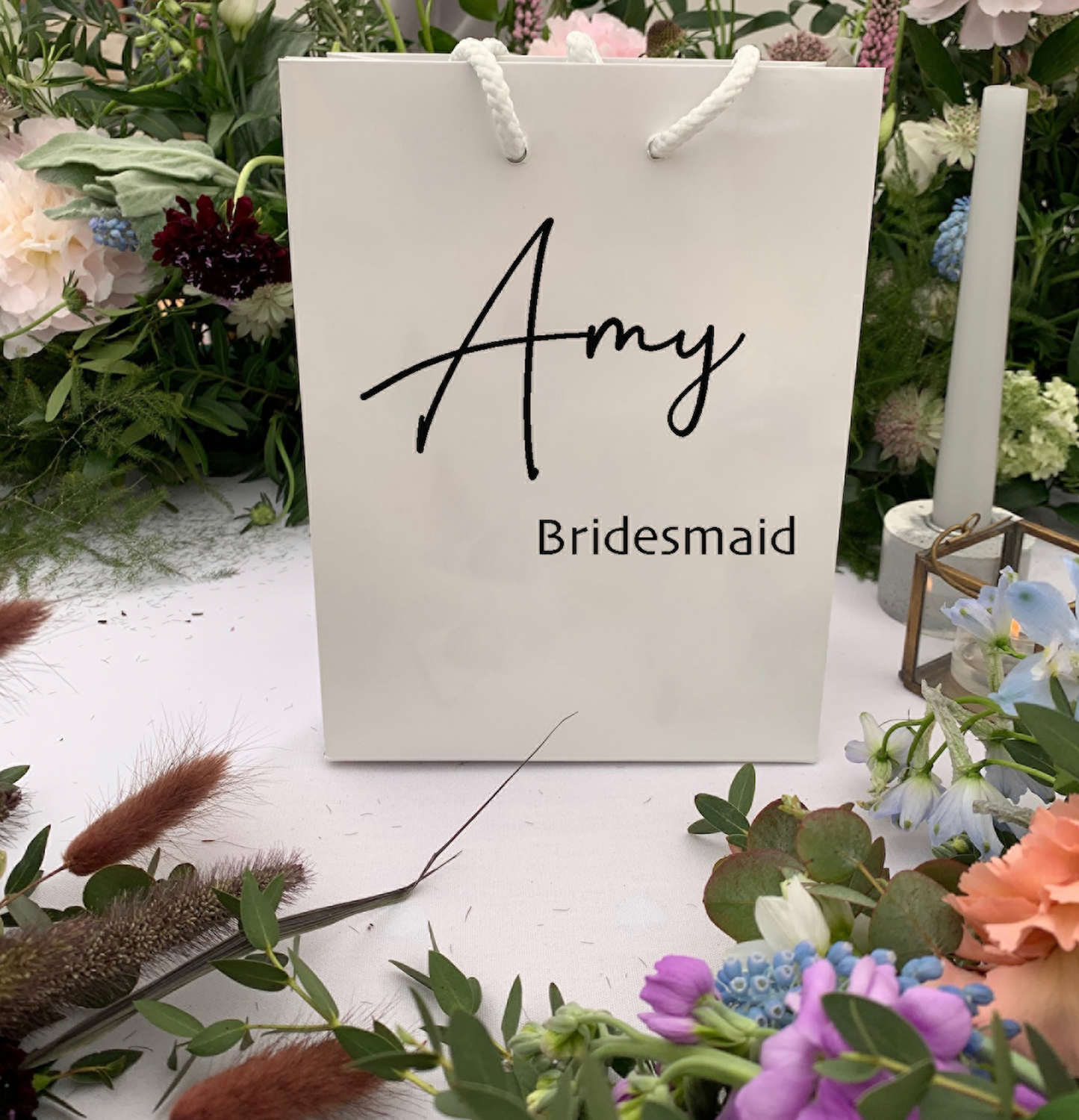 White Gift Bag placed around flowers with black words